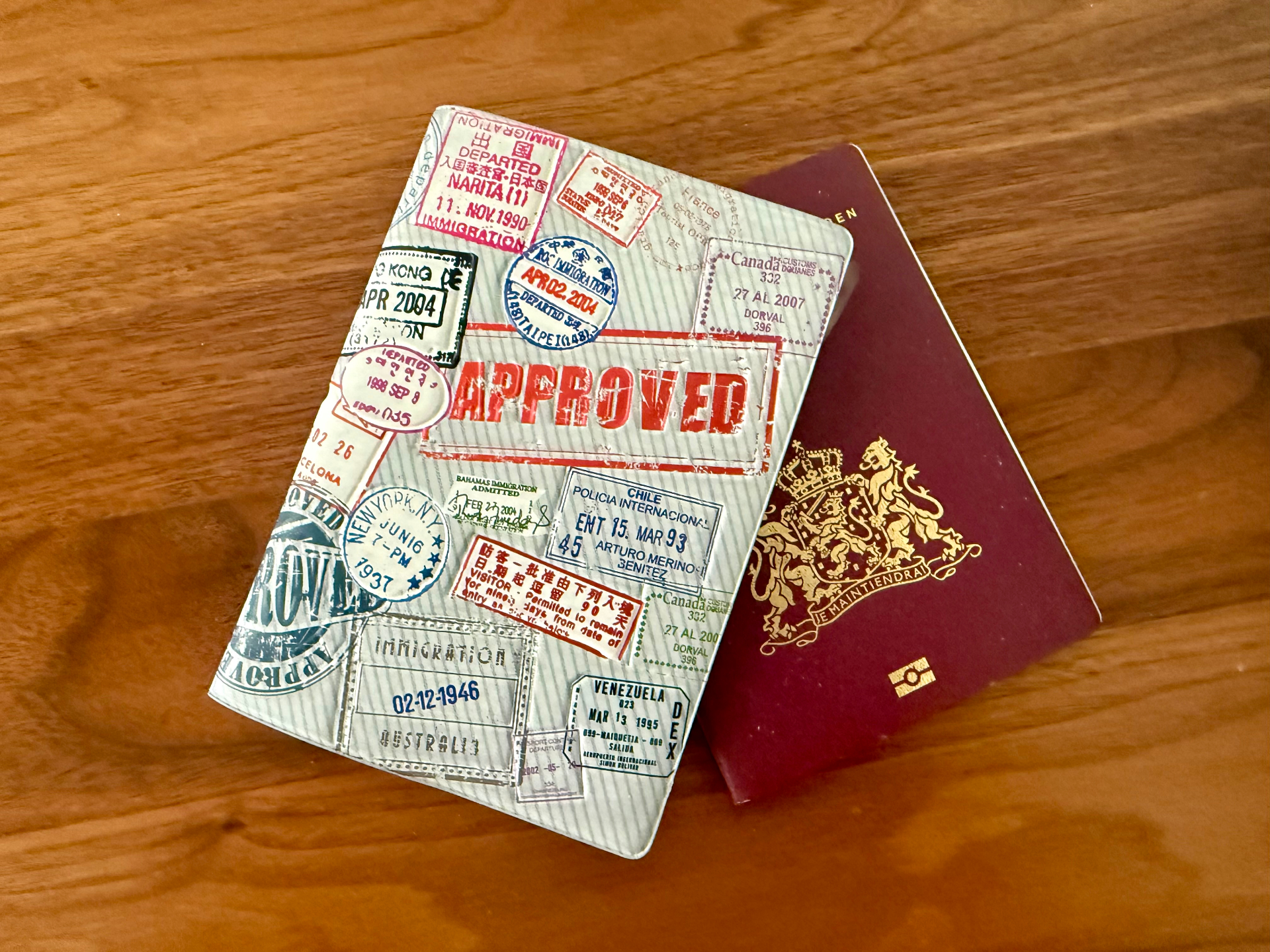 A well-travelled passport cover stacked on a burgundy Dutch European Union passport.
